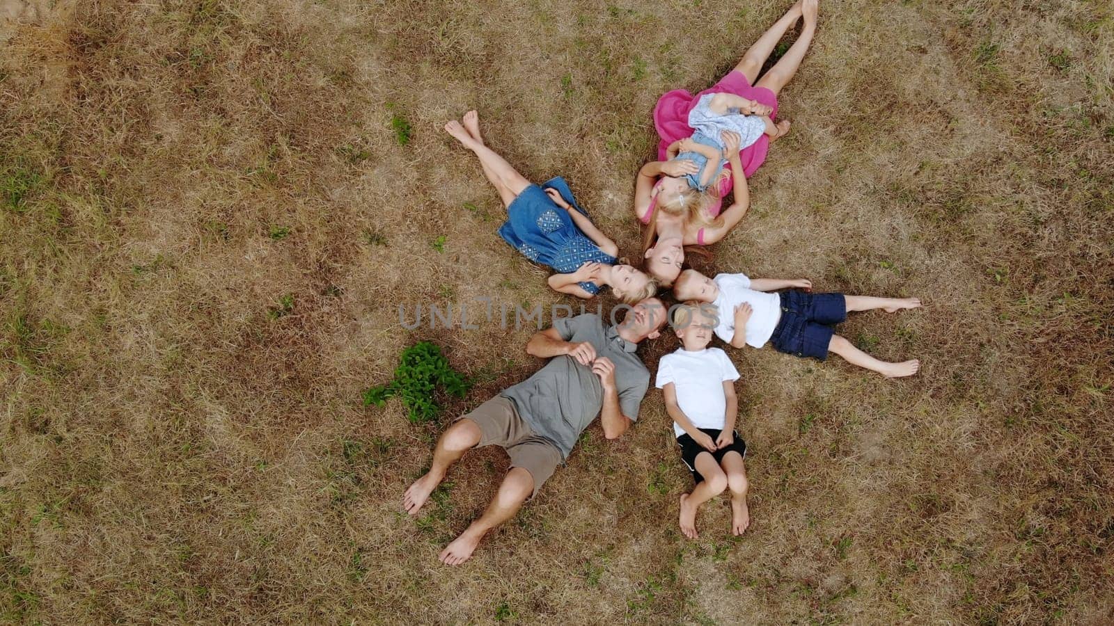 Happy family lies on the grass in the form of sun rays. by DovidPro
