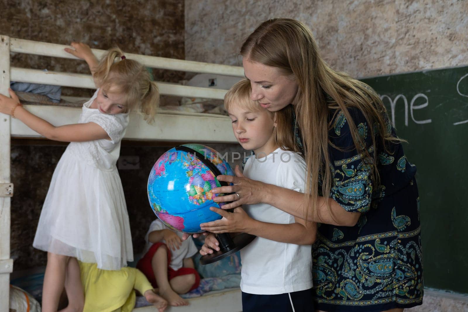 Mother is studying a world map on a globe with her children