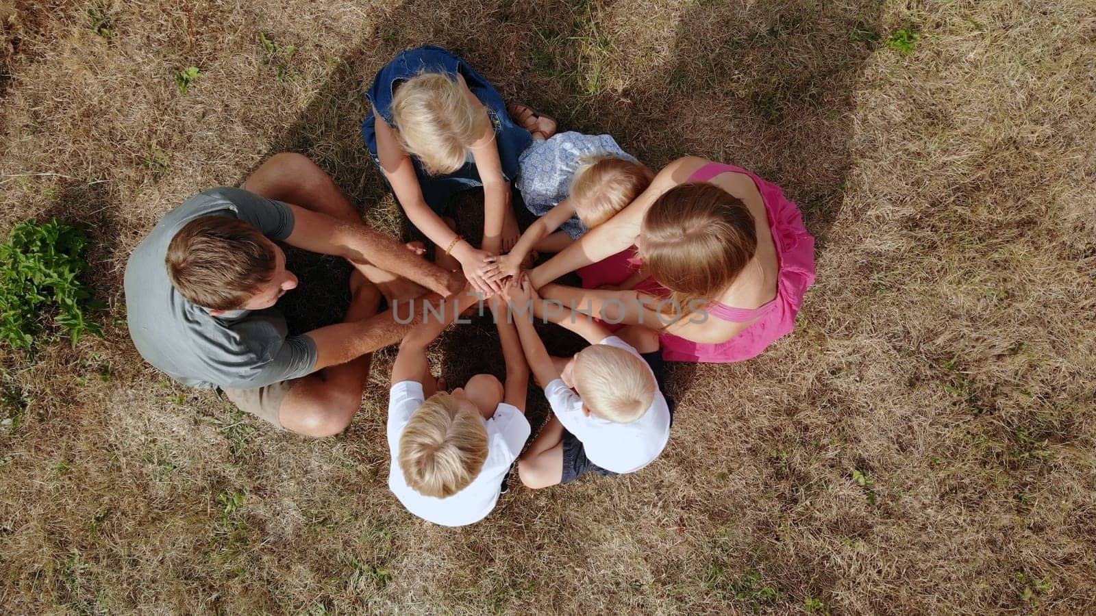 A friendly family joins hands together as a sign of the unity and strength of the family. Drone view. by DovidPro