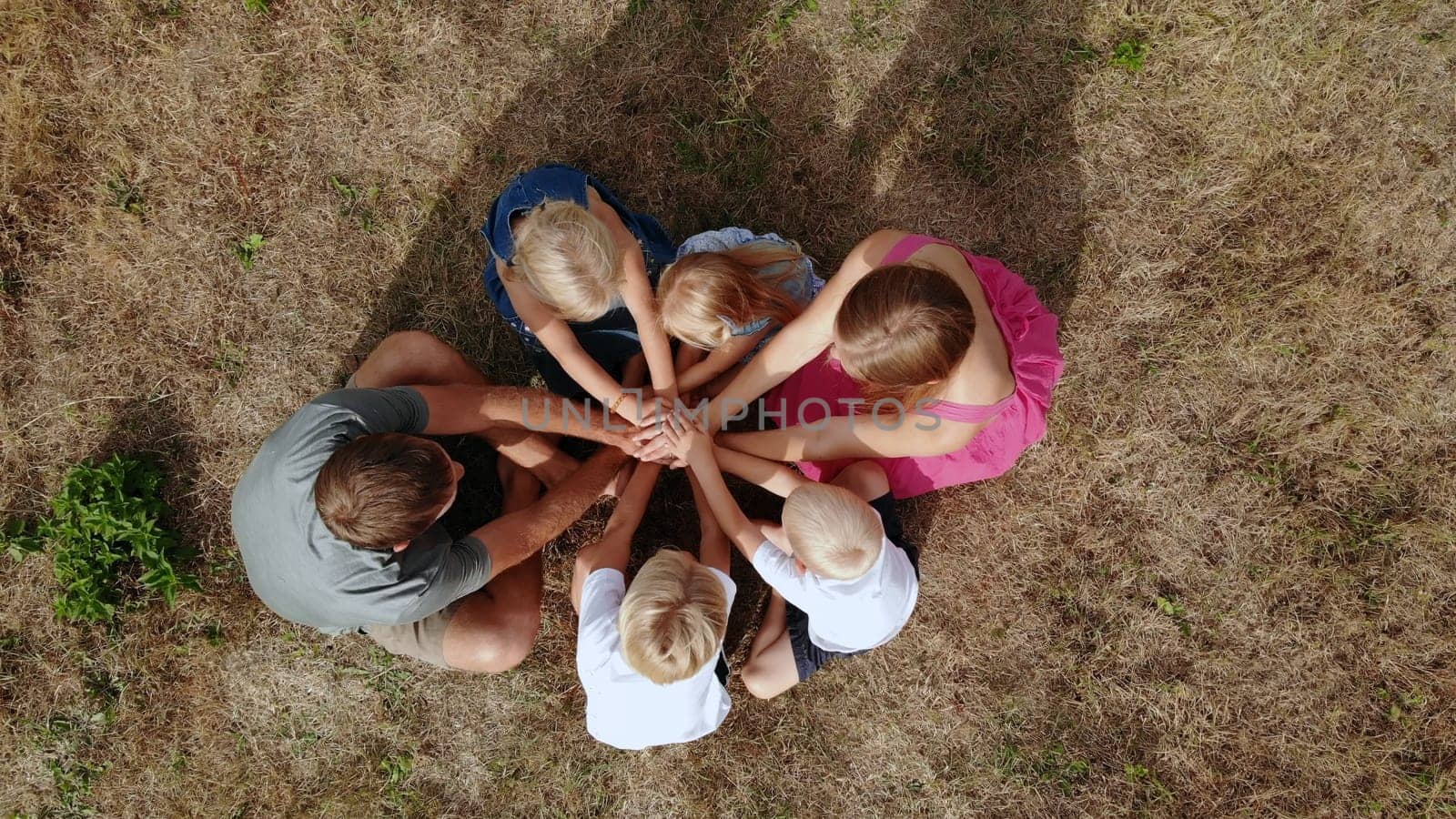 A friendly family joins hands together as a sign of the unity and strength of the family. Drone view
