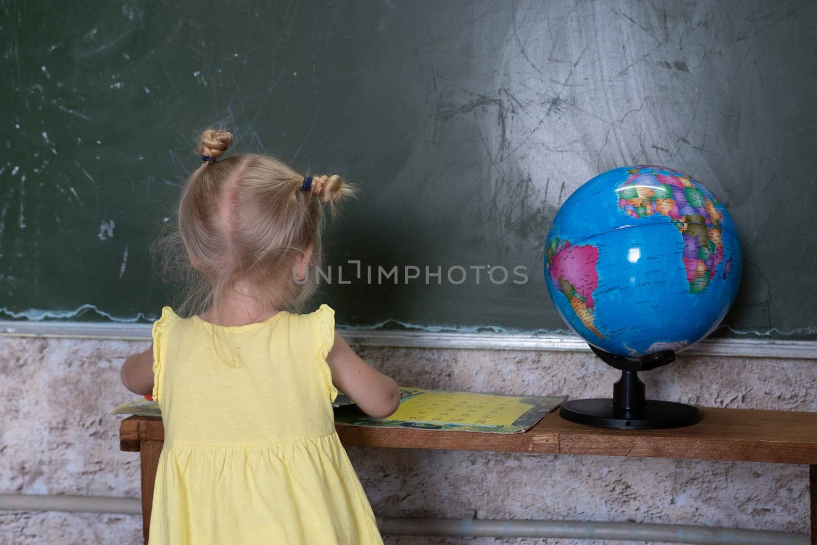 A little girl is engaged with a book on the background of a world globe