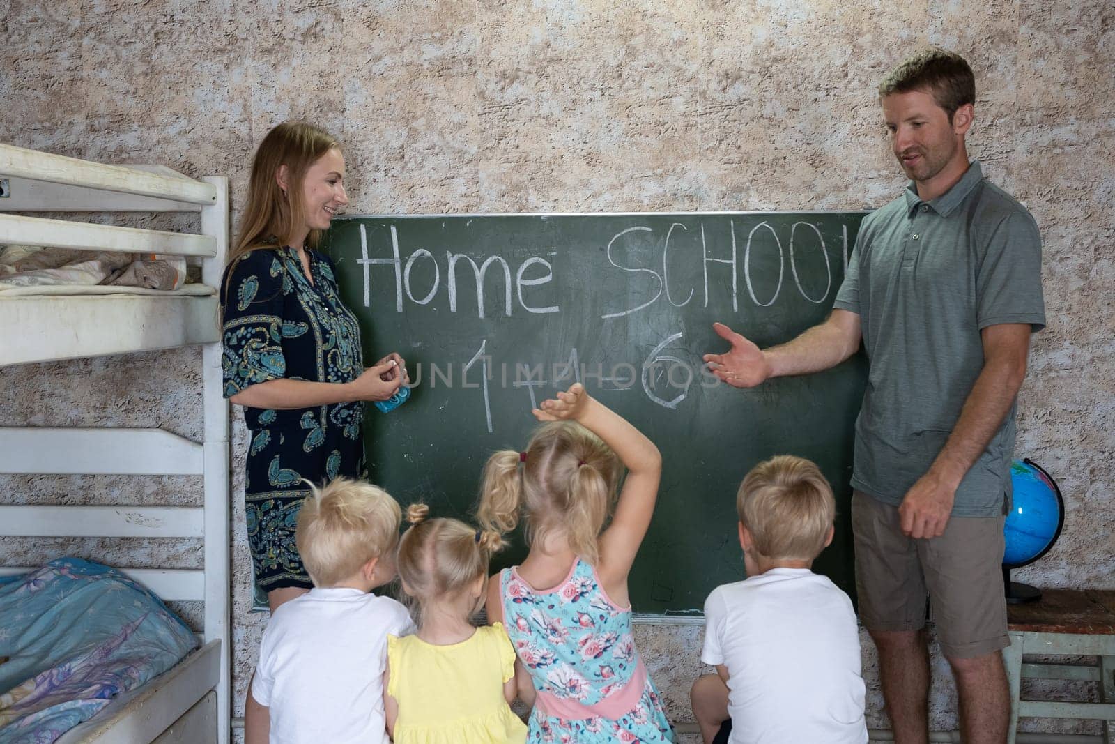 Parents teach their children at the blackboard in their home. Home school. by DovidPro
