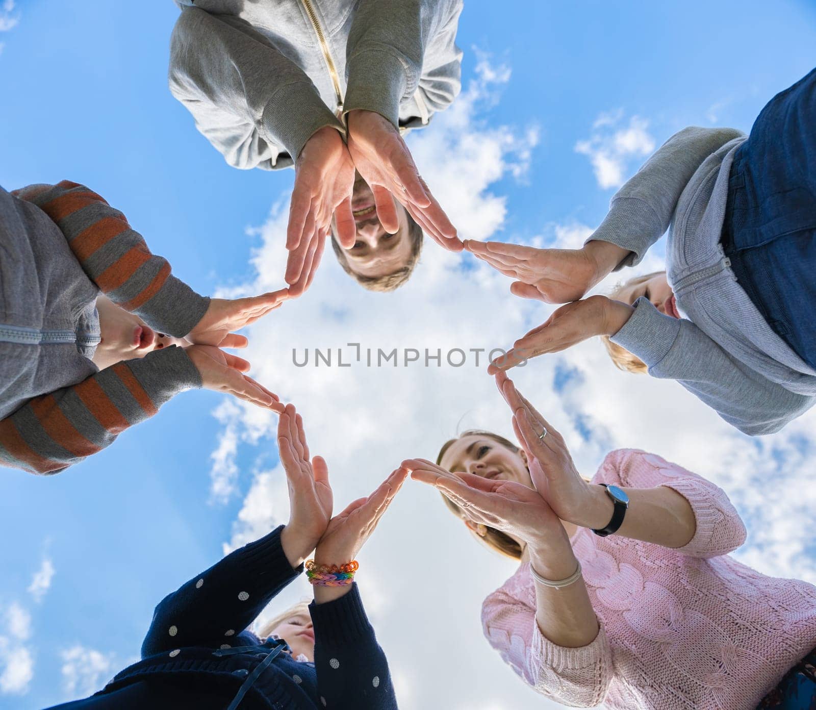 A friendly family makes a star shape out of their hands. by DovidPro
