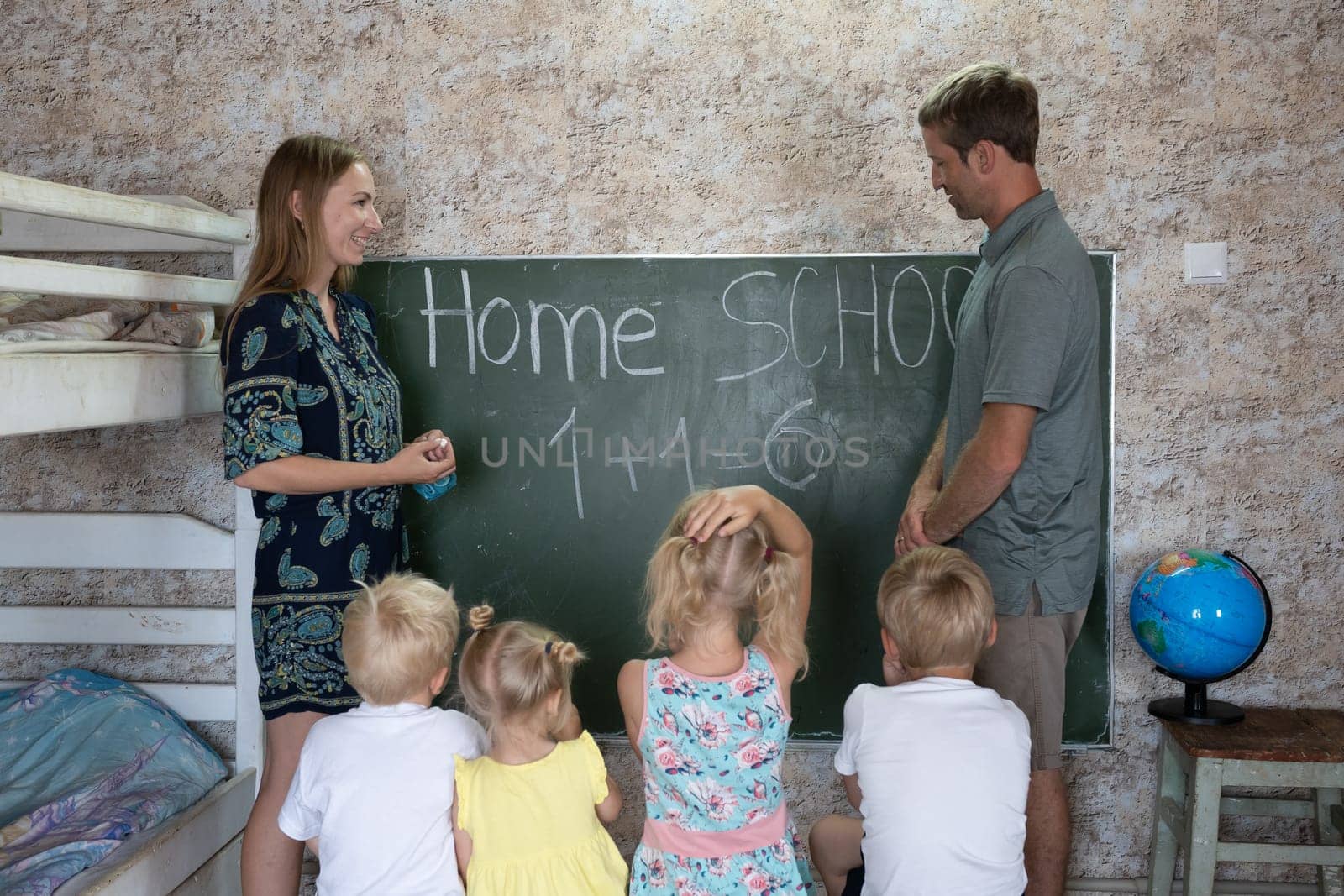 Parents teach their children at the blackboard in their home. Home school