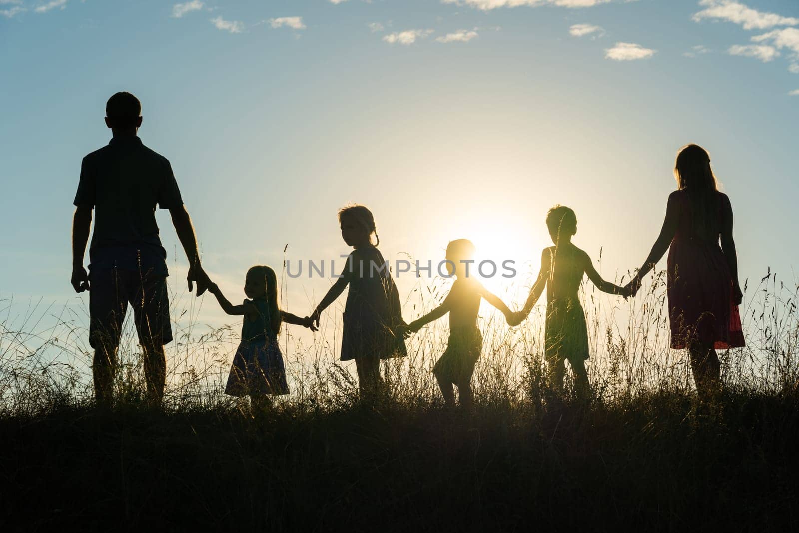 Silhouette of a happy large family at sunset. by DovidPro