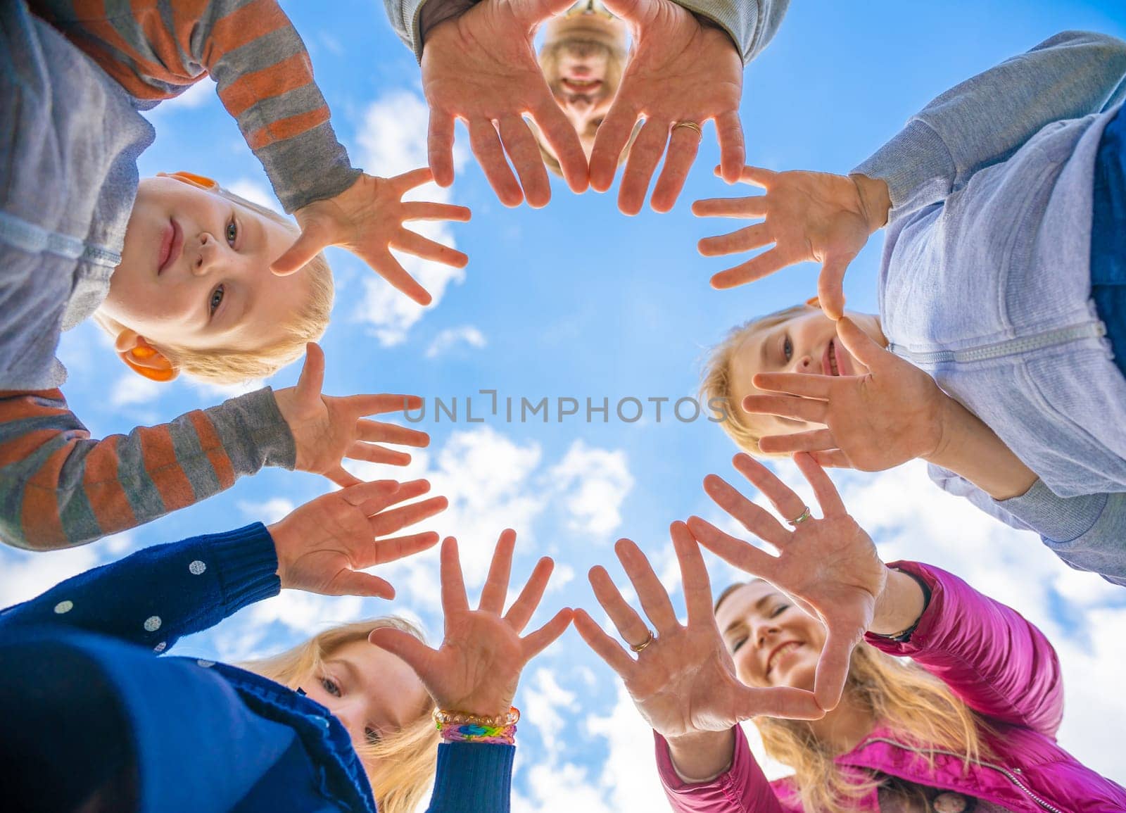 A friendly large family makes a circle shape out of the palms of their hands. by DovidPro
