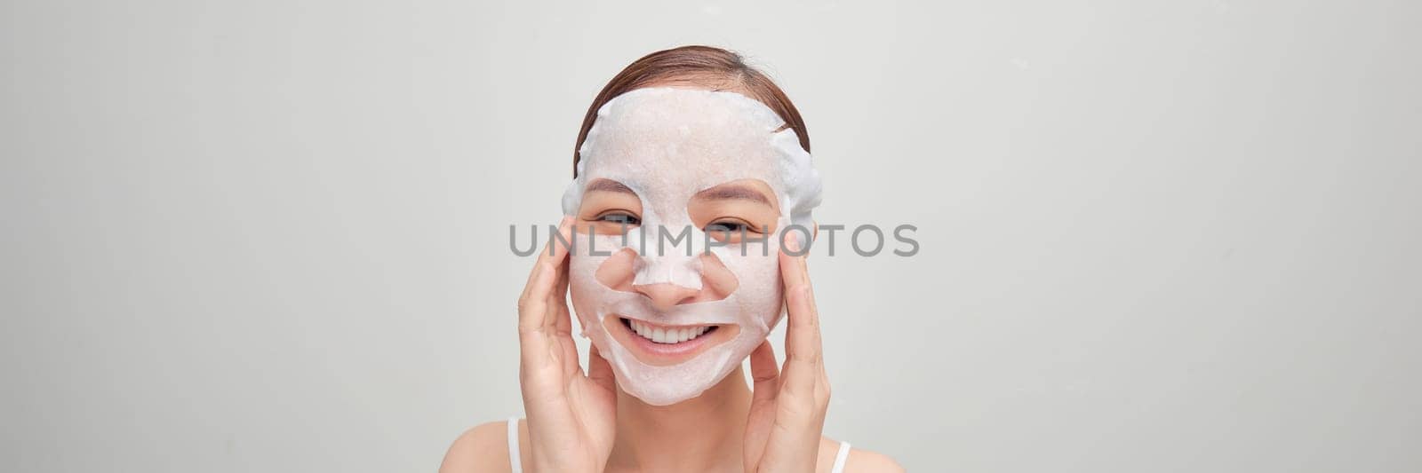 Woman with a sheet moisturizing mask on her face isolated on white background by makidotvn