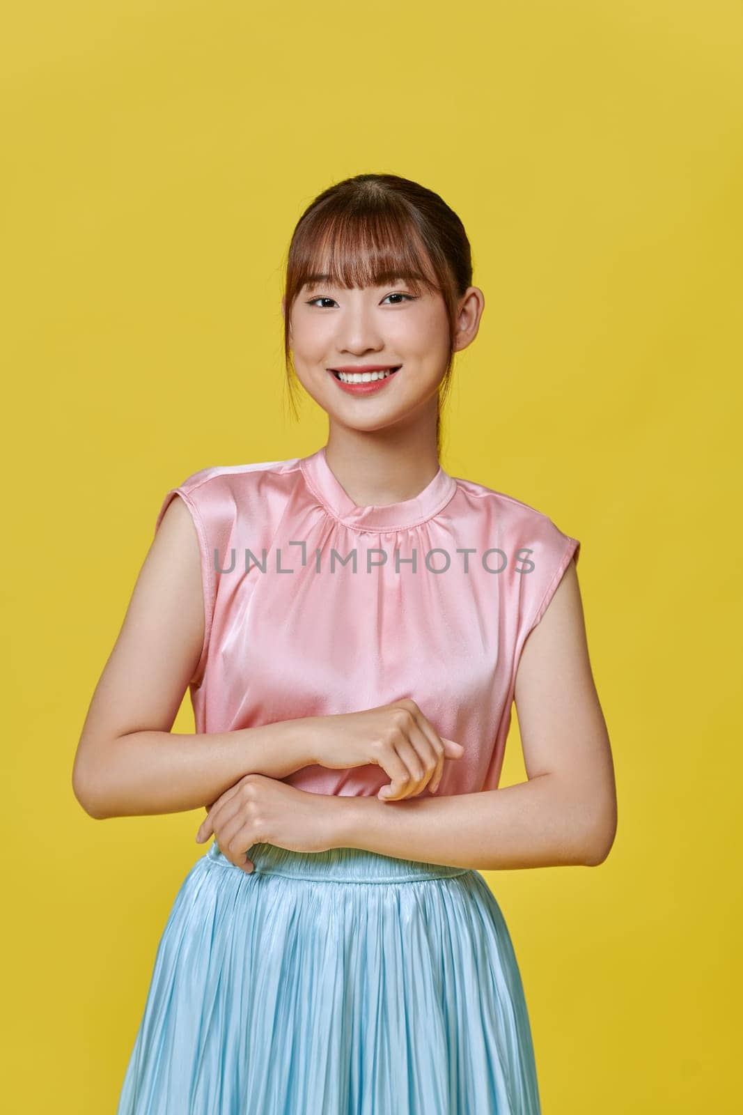 Smiling beautiful attractive young woman in silk casual dress posing  isolated on yellow background by makidotvn