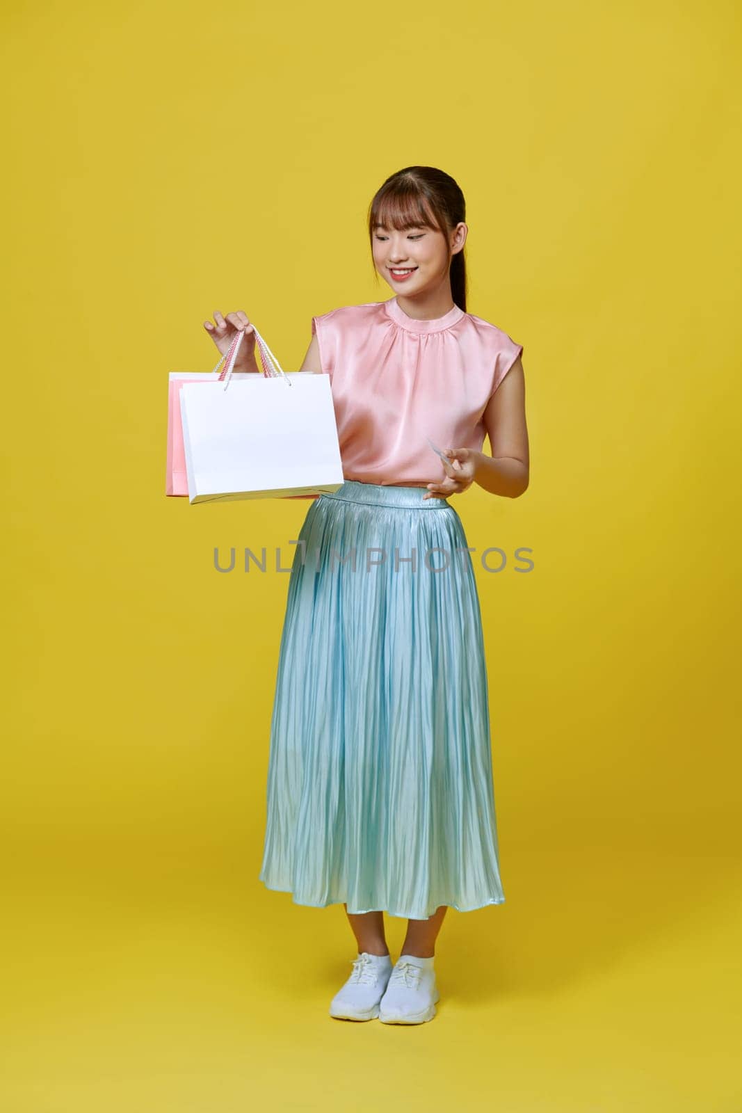 Excited smile Asian woman looking mobile phone holding shopping bag show credit card payment banking shopping online