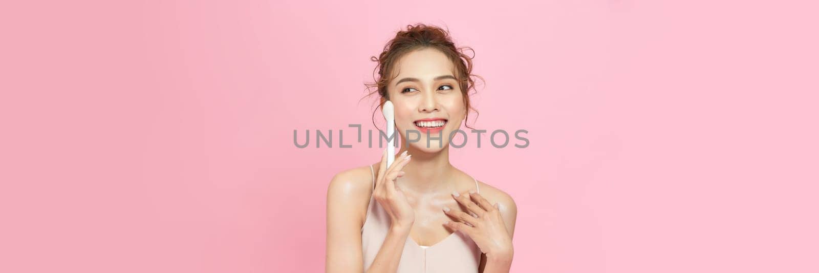 Closeup portrait of beautiful happy young girl with perfect skin is holding makeup brush in hand. by makidotvn