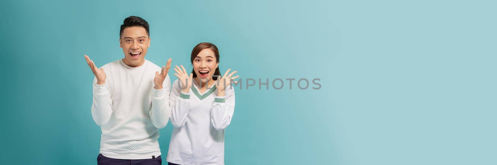 Portrait of Asian couple with surprised and excited expression isolated on turquoise banner by makidotvn