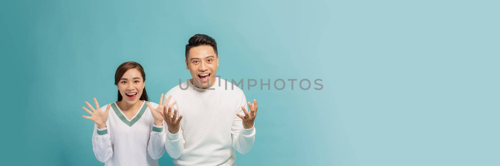 Portrait of Asian couple with surprised and excited expression isolated on turquoise banner
