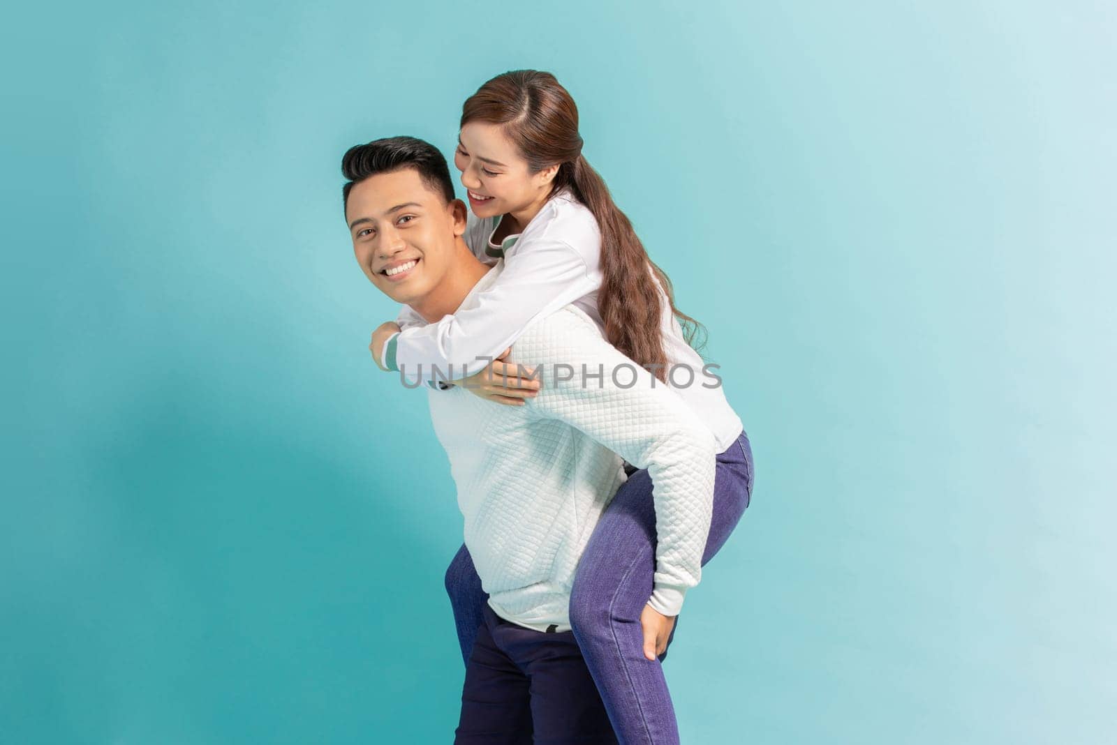 Handsome man giving piggy back to his girlfriend on color by makidotvn