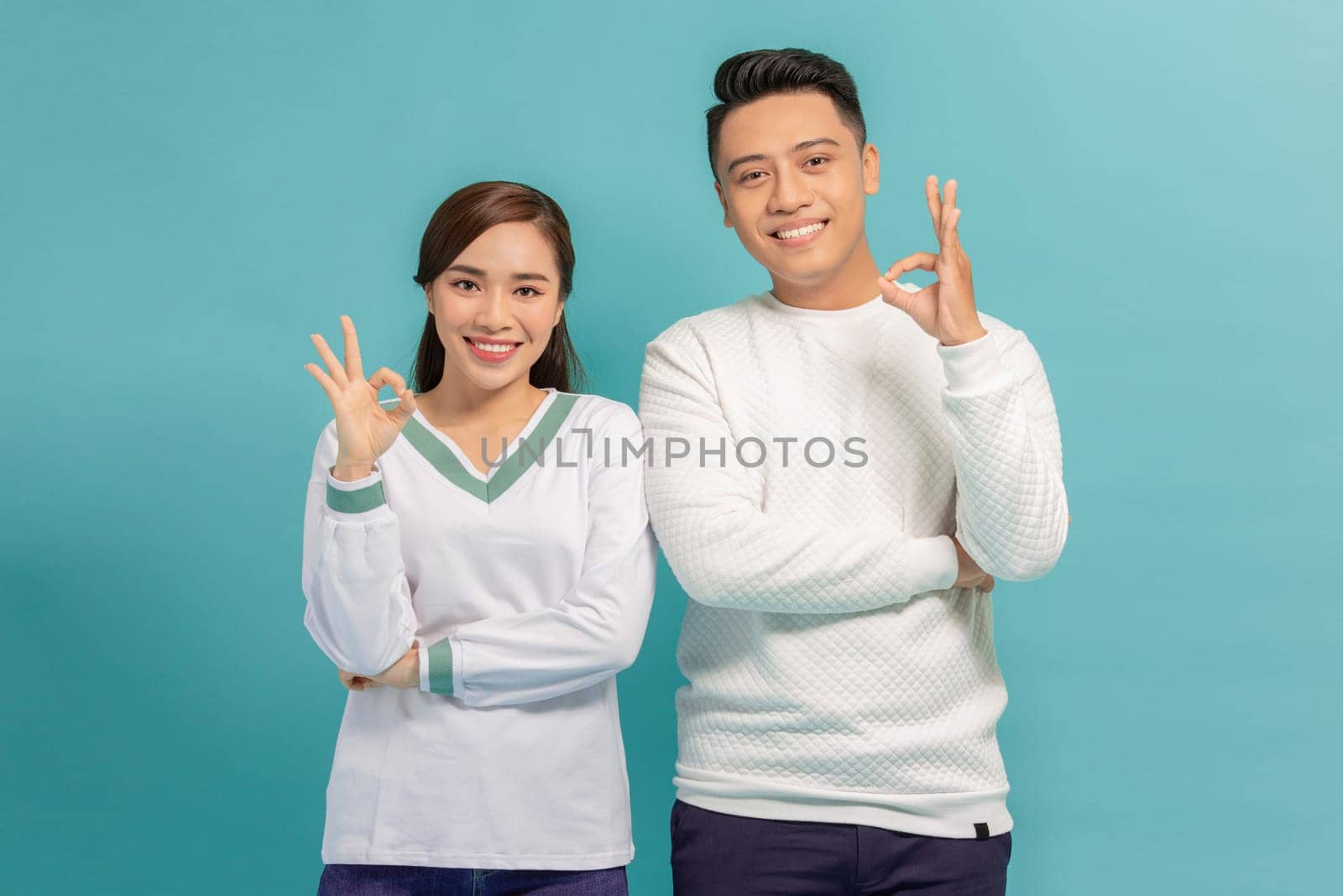Portrait of young Asian couple showing ok sign isolated on  blue background, Two people concept