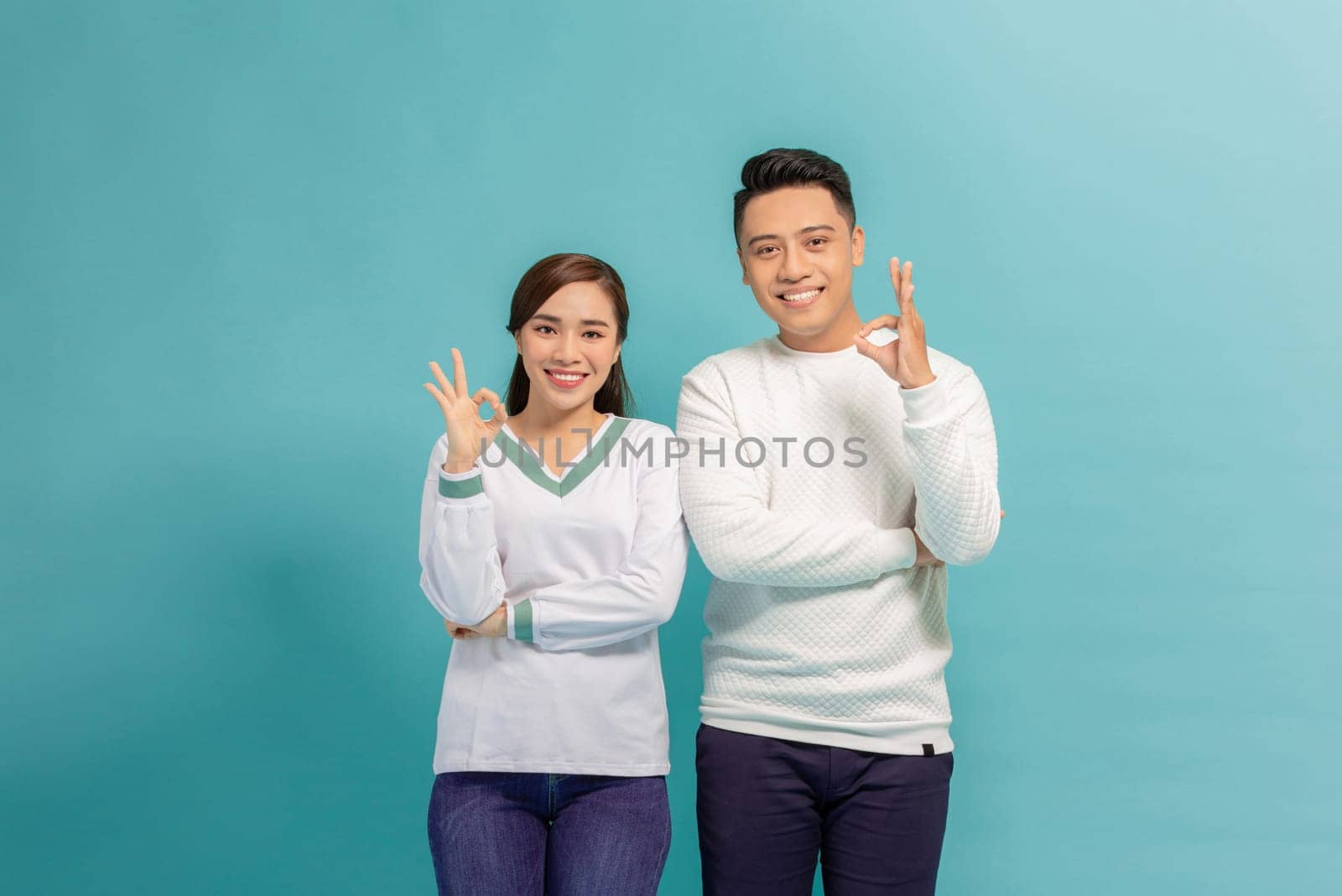 Young couple standing together smiling positive doing ok sign with hand and fingers by makidotvn