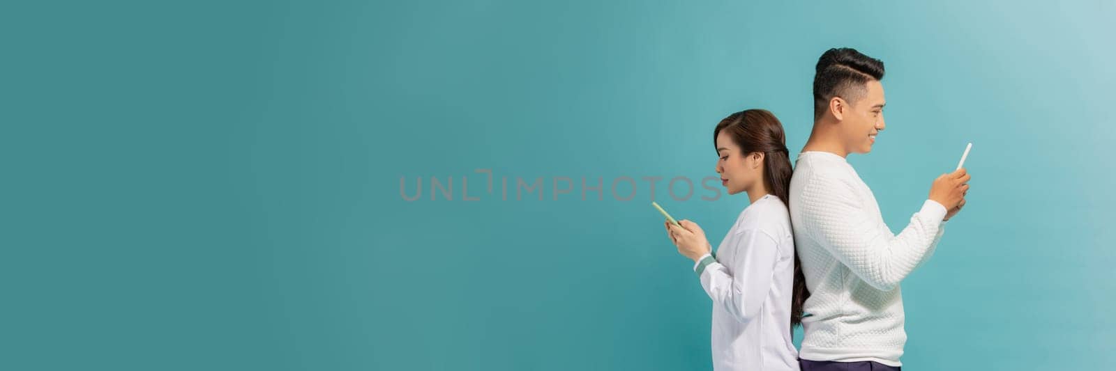 Attractive young couple are looking at smartphone on blue background