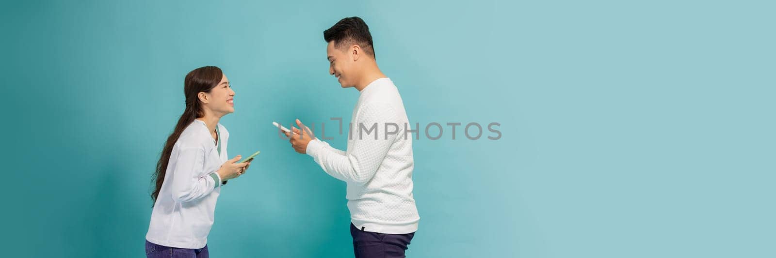 Internet addicted. Two young lovers are busy at their mobile phones in social nets on blue banner by makidotvn