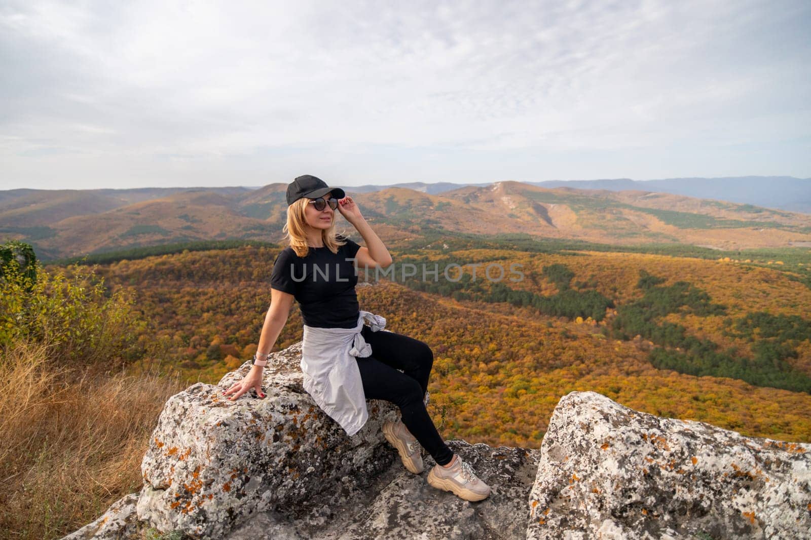 woman on mountain peak looking in beautiful mountain valley in autumn. Landscape with sporty young woman, blu sky in fall. Hiking. Nature.