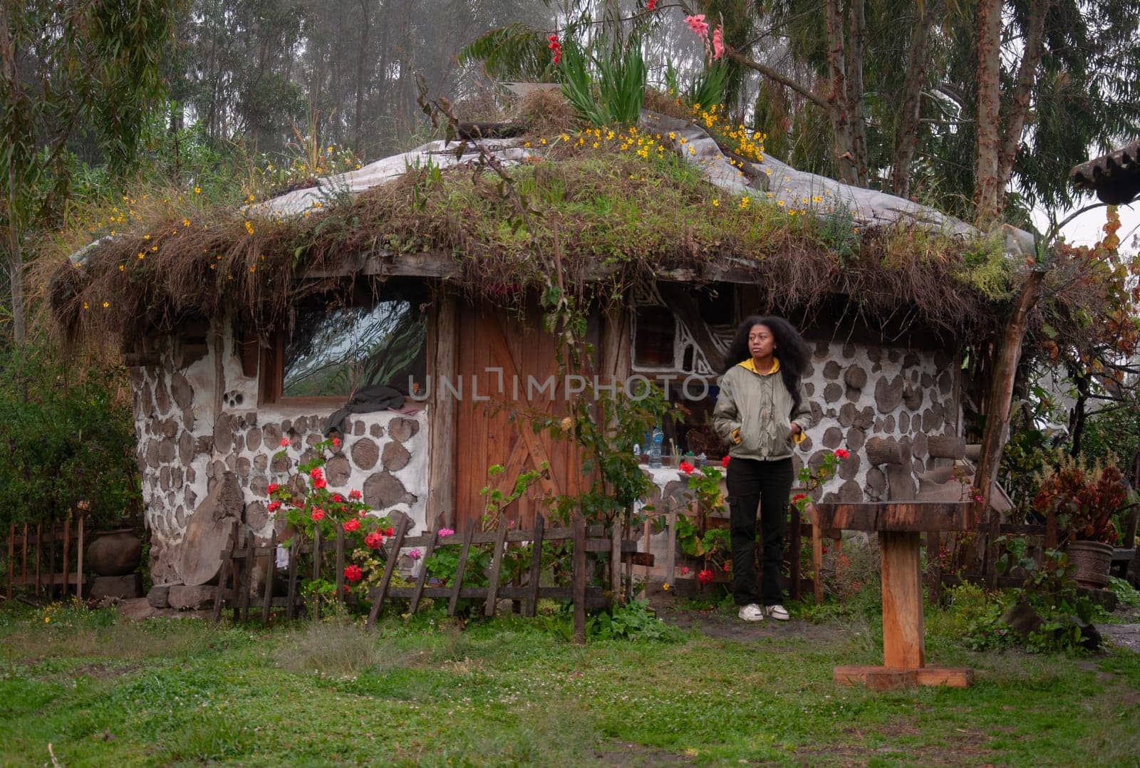 paradisiacal rural tourism: african-american woman staying in a cabin in a rural resort where the cabins are round and the roof is adorned with colorful flowers. tourism day. High quality photo