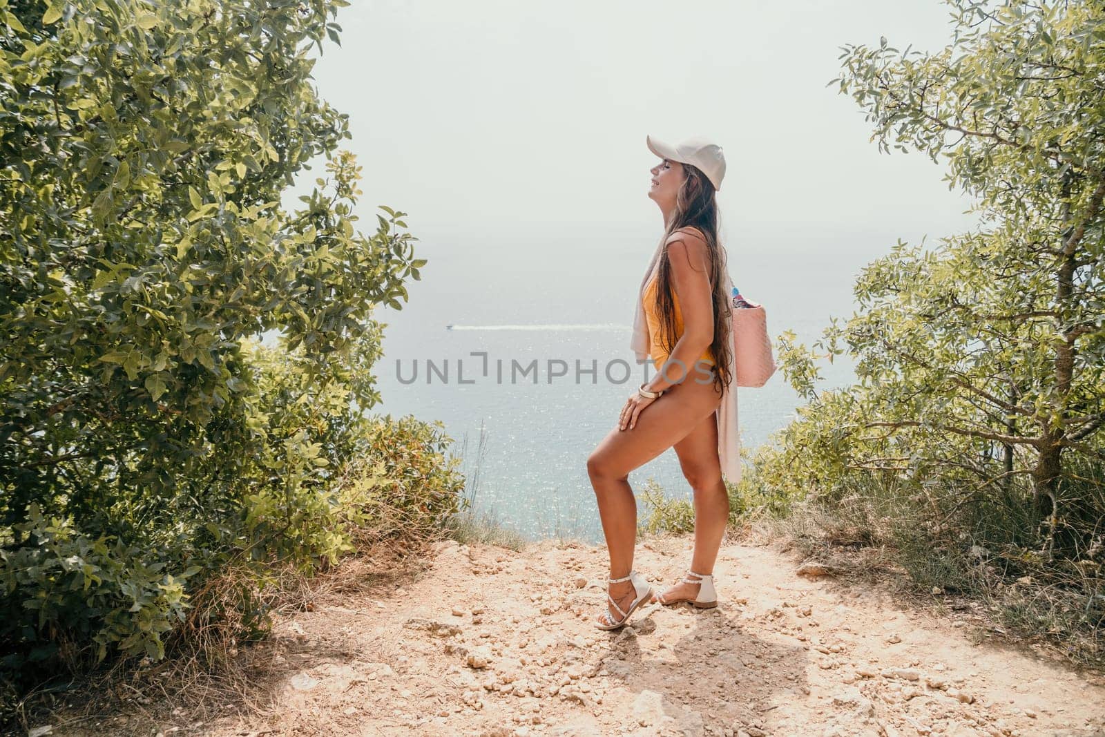 Woman travel sea. Happy tourist enjoy taking picture outdoors for memories. Woman traveler looks at the edge of the cliff on the sea bay of mountains, sharing travel adventure journey by panophotograph