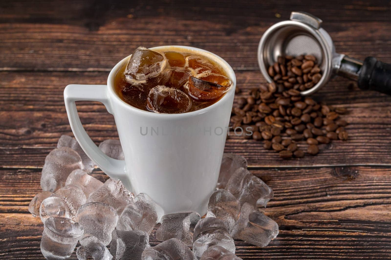 A cup of Iced Americano Coffee with ice cubes placed on a wooden table in a coffee shop. Top view of a glass of coffee.
