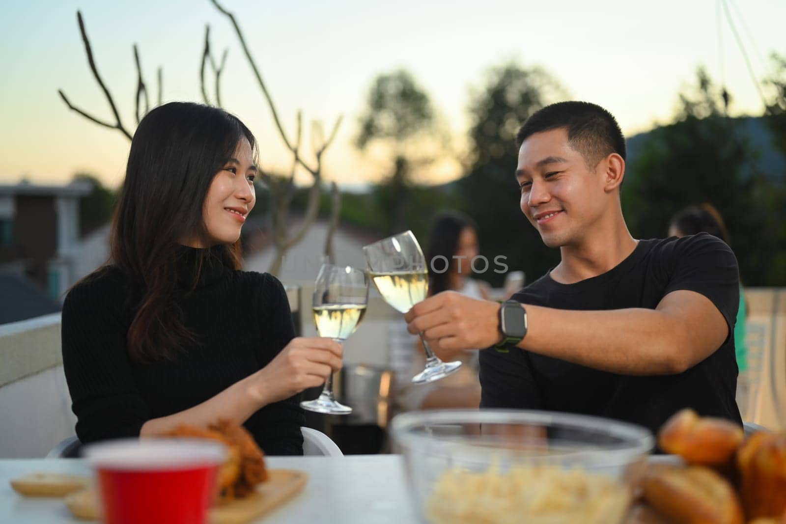 Young Asian couple having fun at a summertime rooftop party during sunset