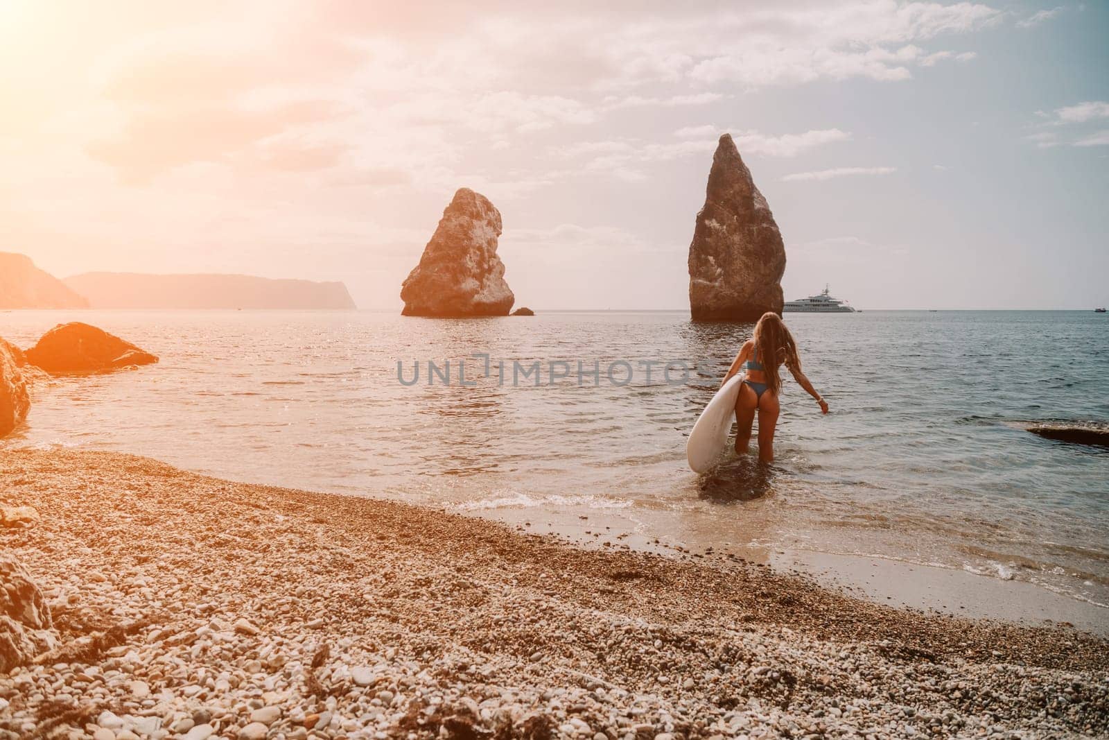 Close up shot of beautiful young caucasian woman with black hair and freckles looking at camera and smiling. Cute woman portrait in a pink bikini posing on a volcanic rock high above the sea