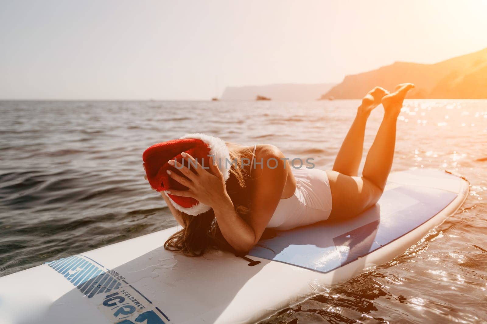 Close up shot of happy young caucasian woman looking at camera and smiling. Cute woman portrait in bikini posing on a volcanic rock high above the sea