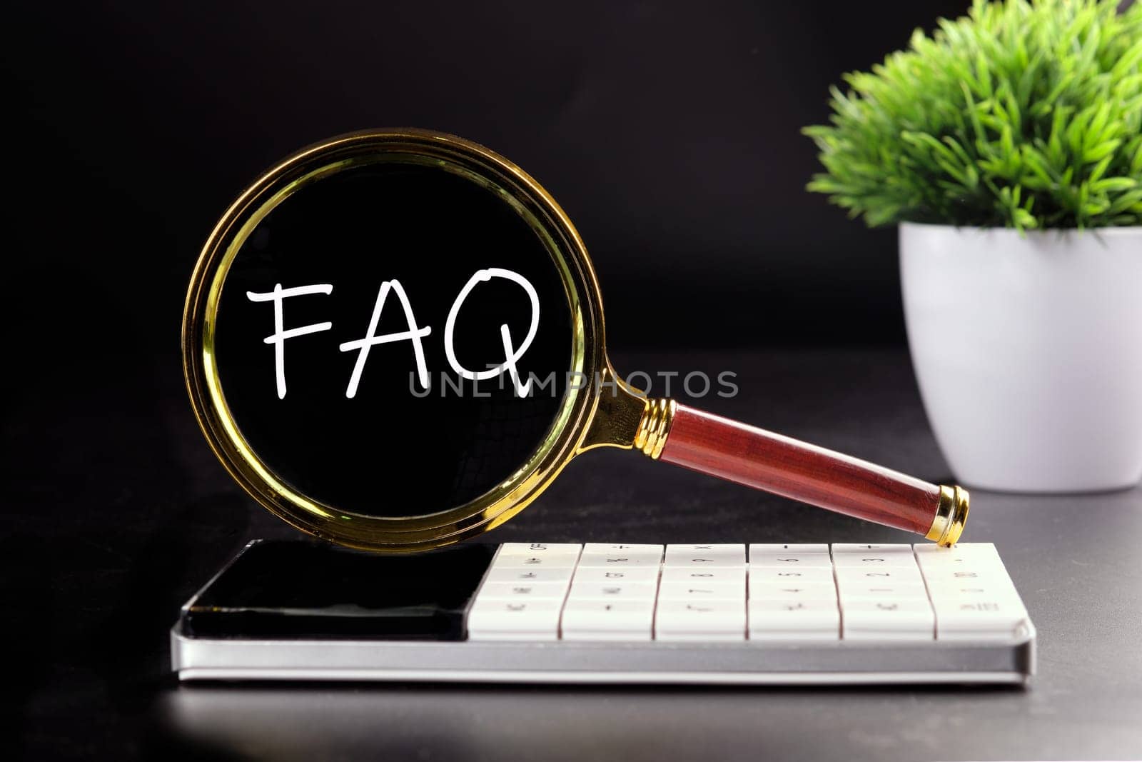FAQ text seen with a magnifying glass on a black background