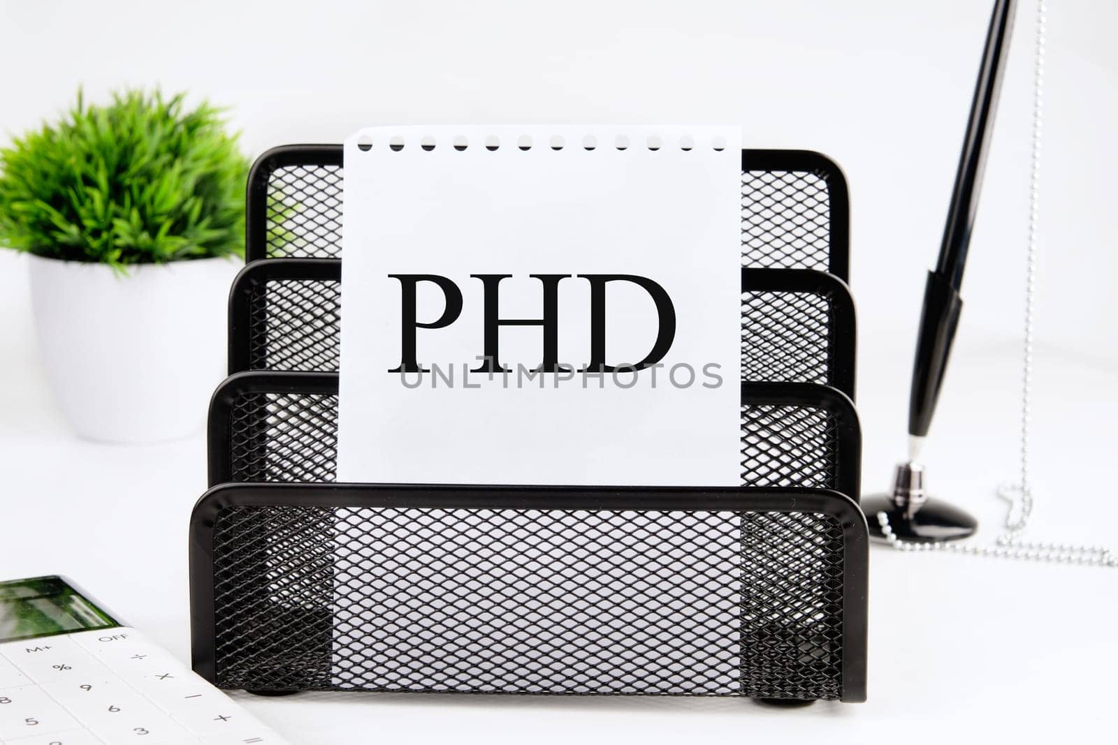PHD A word written on a piece of paper from a notebook on a stand on a white background