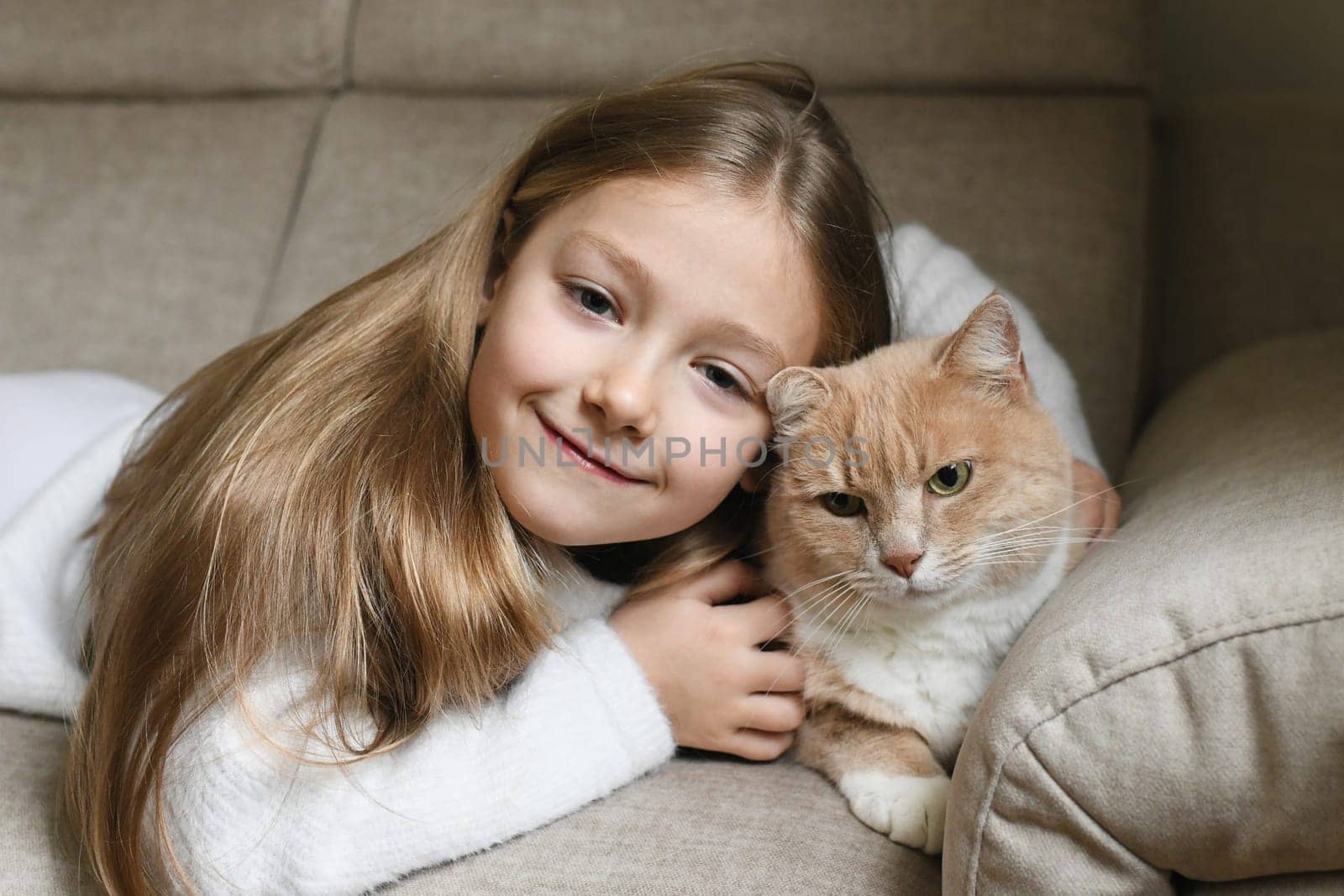 A girl near a ginger cat on the sofa