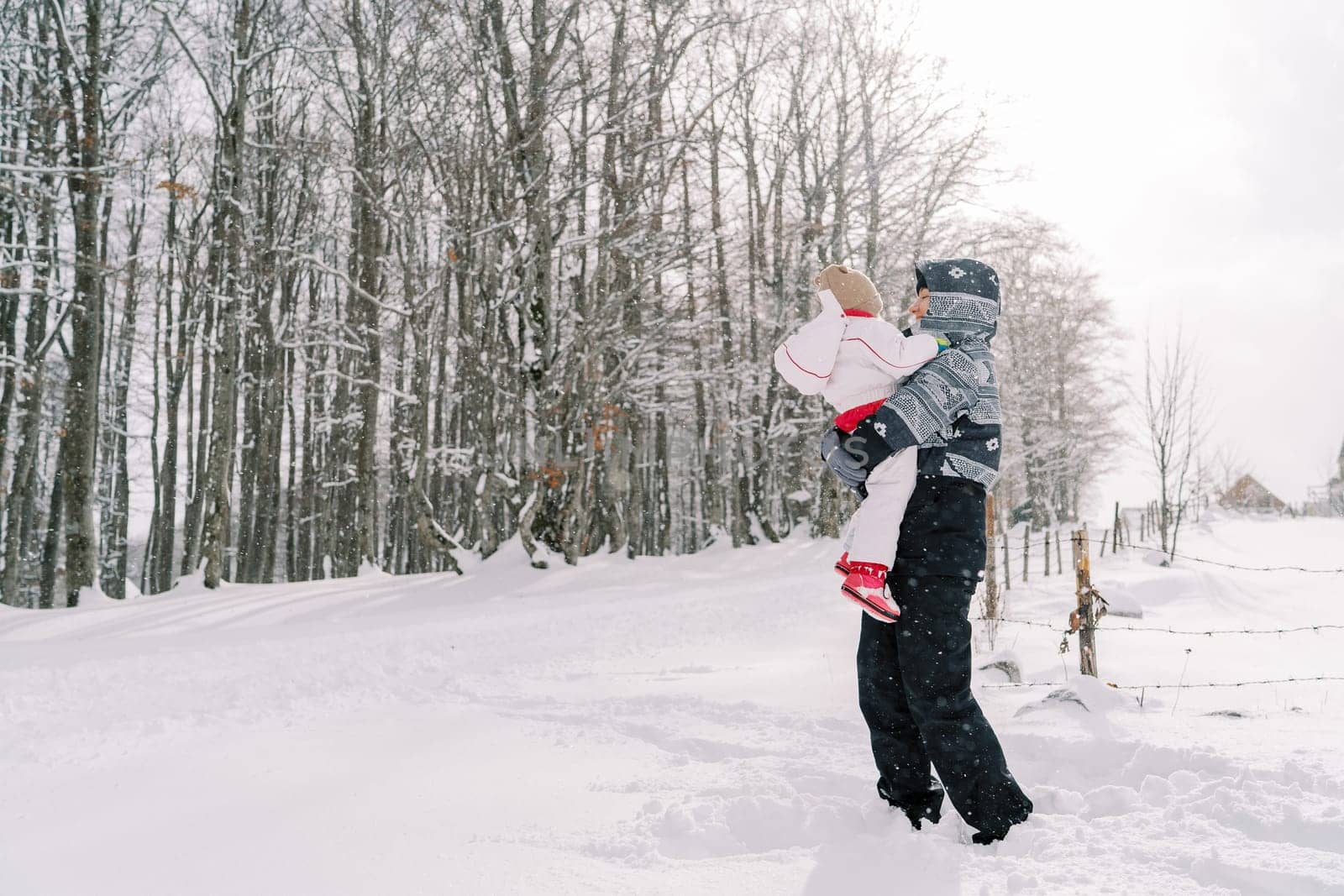 Mother with a little girl in her arms stands in a snowdrift on a snowy road. High quality photo