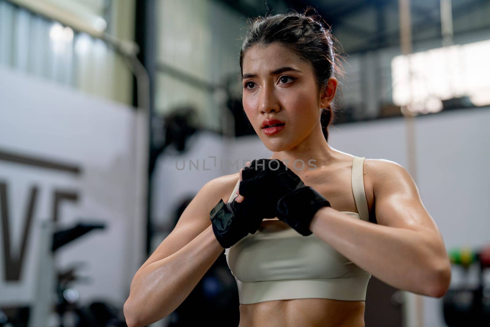 Portrait of Asian sport woman clenched fist and look forward with serious and spirited also stand in fitness gym.