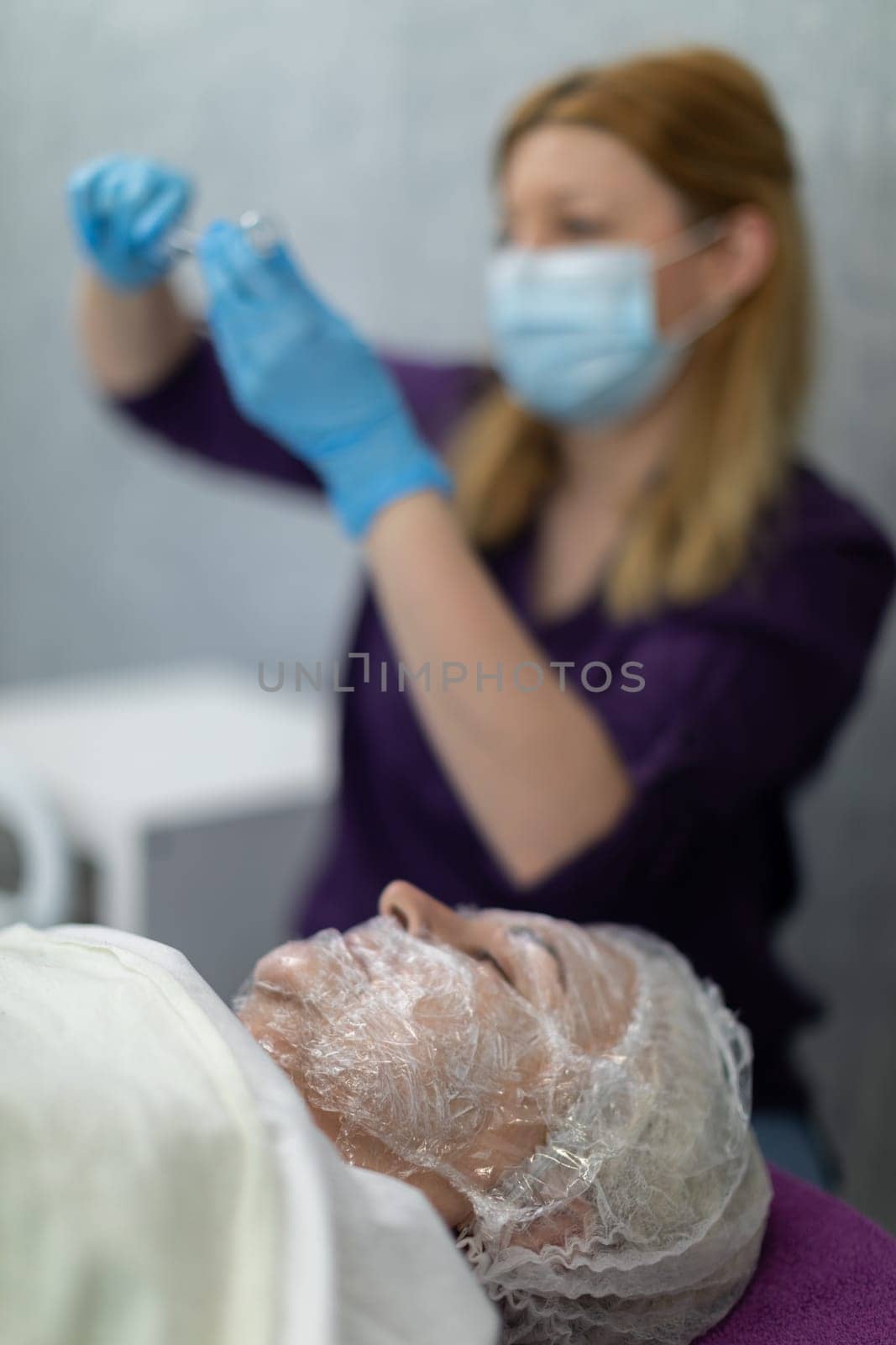 A specialist at an aesthetic clinic prepares a patient for a beauty treatment. by fotodrobik