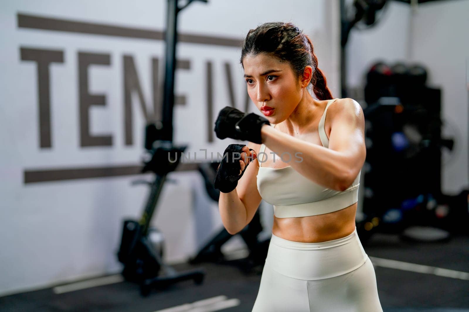 Asian woman action of boxing and training alone in fitness gym and she look concentrate to practice for competition.