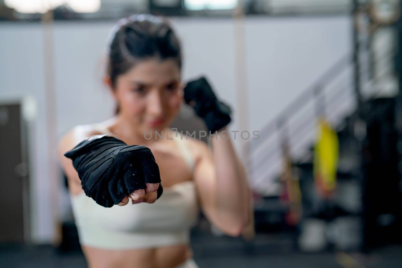 Close up hands of Asian woman action of puch and hit also look at camera with smiling in fitness gym.