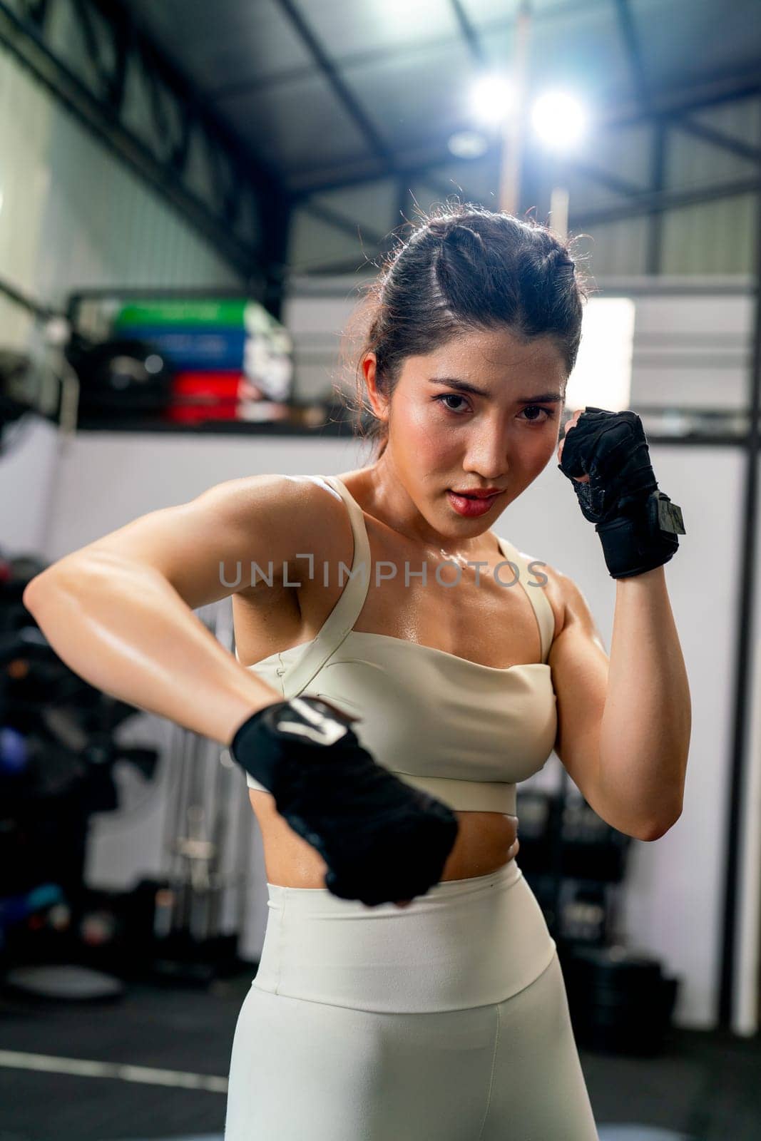 Asian woman action of boxing and training alone in fitness gym and she look concentrate to practice for competition.