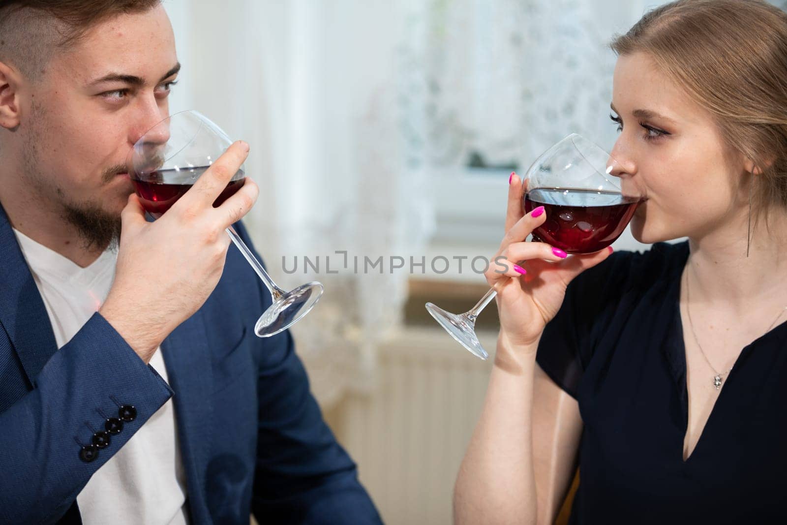 A man and a woman drink red wine at an elegant family gathering. by fotodrobik