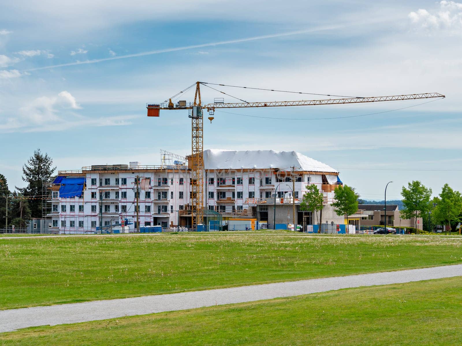 New low-rise residential building under construction with recreational green lawn in front.
