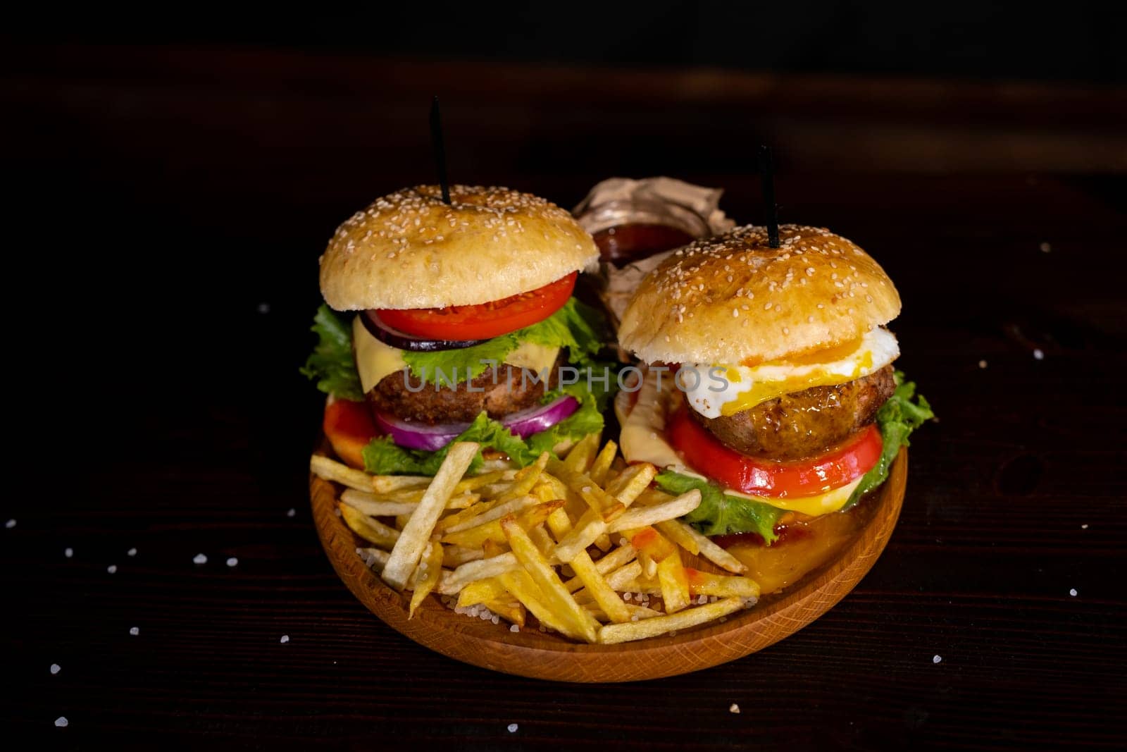 Burger, hamburger with egg or cheeseburger served with french fries, pickles and onion on wooden board. Top view. Fast food concept. High quality photo