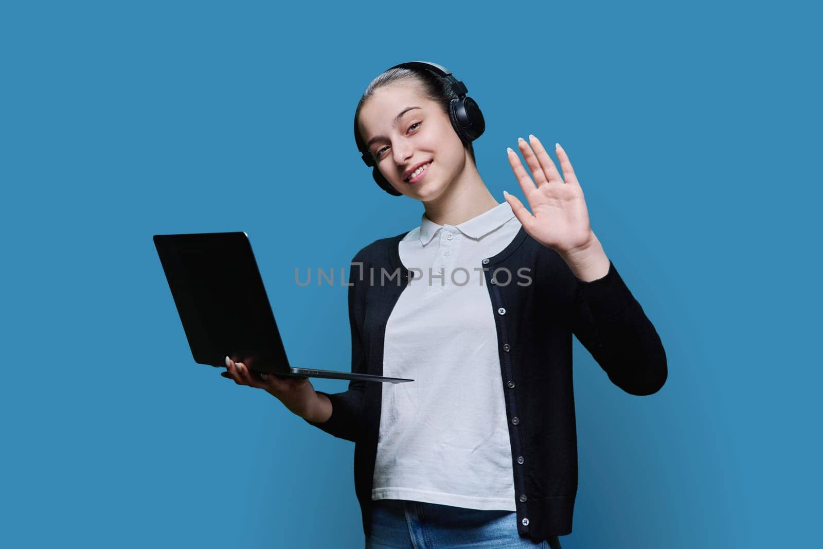 Teen girl student wearing headphones using laptop, on blue background by VH-studio