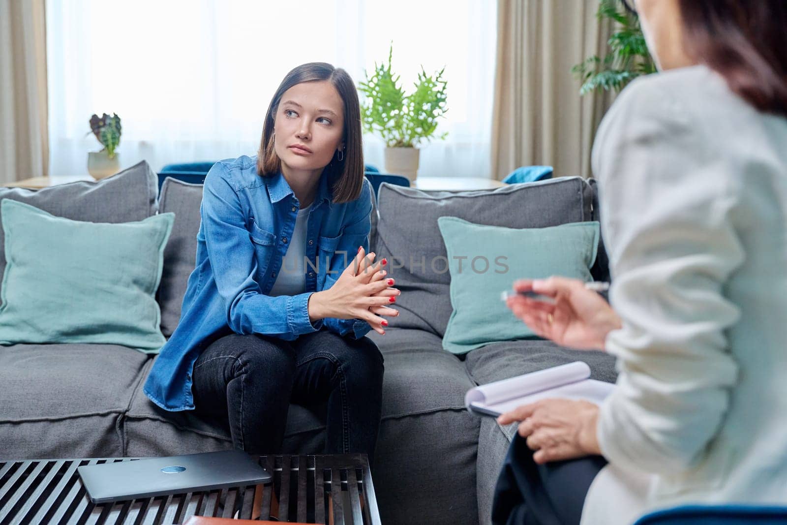 Sad young woman at therapy session with psychologist by VH-studio