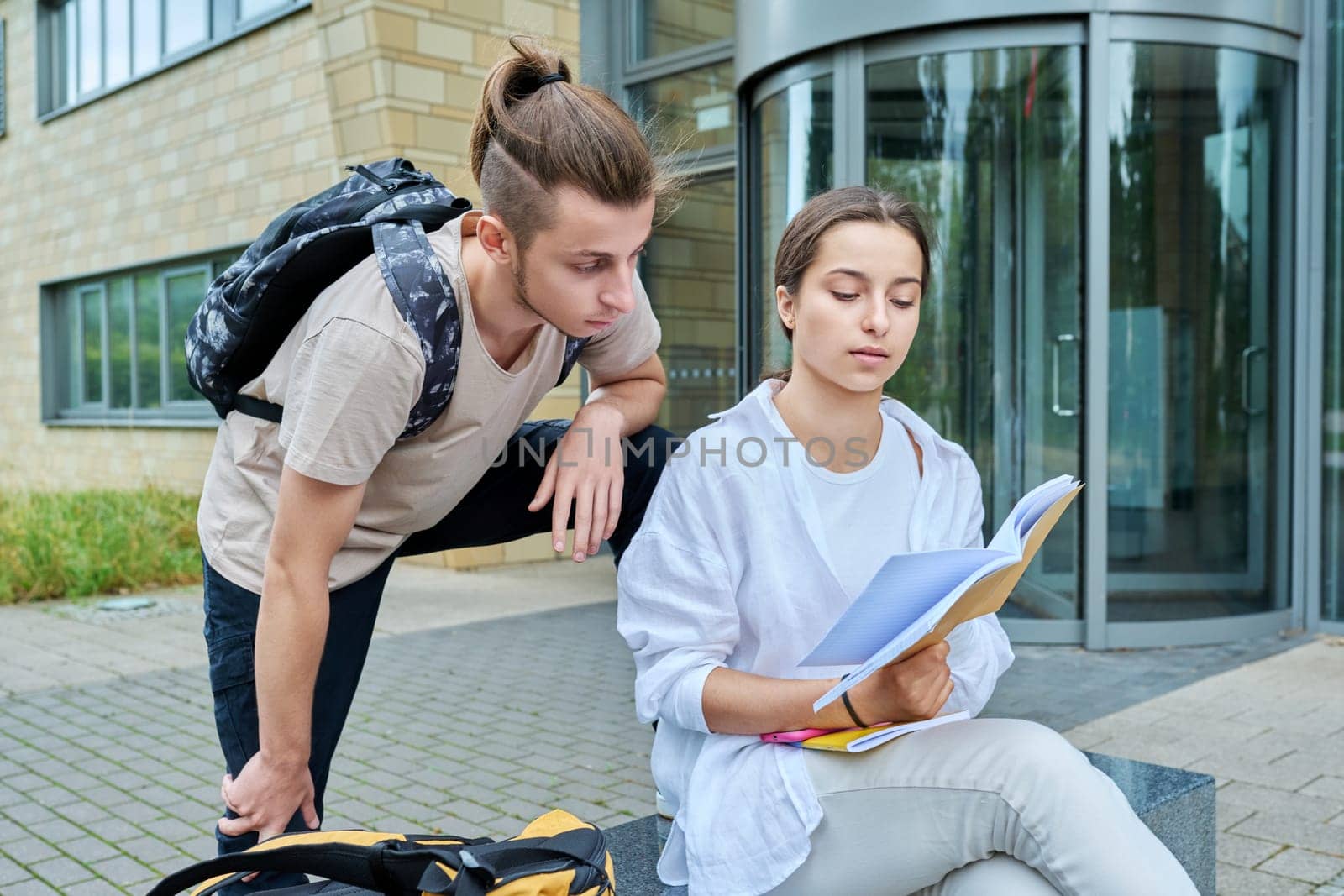 Two high school students guy and girl outdoor, school building background by VH-studio