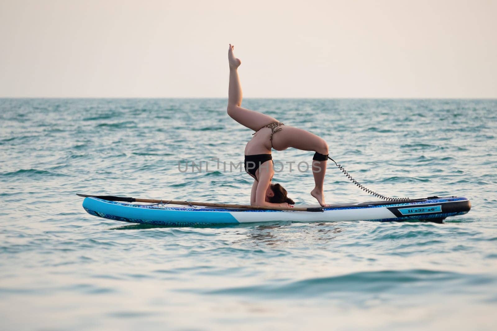sporty girl on a sup board with a paddle in the sea does yoga