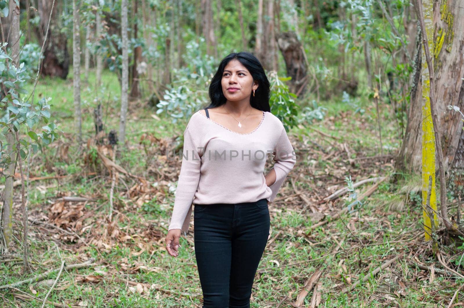 beautiful ecuadorian woman in an ancient forest admiring the peaceful and quiet place that surrounds her. earth day. High quality photo