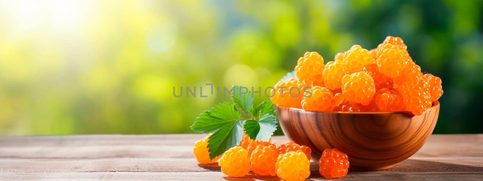 Cloudberry berries in a bowl against the backdrop of the garden. Selective focus. Food.