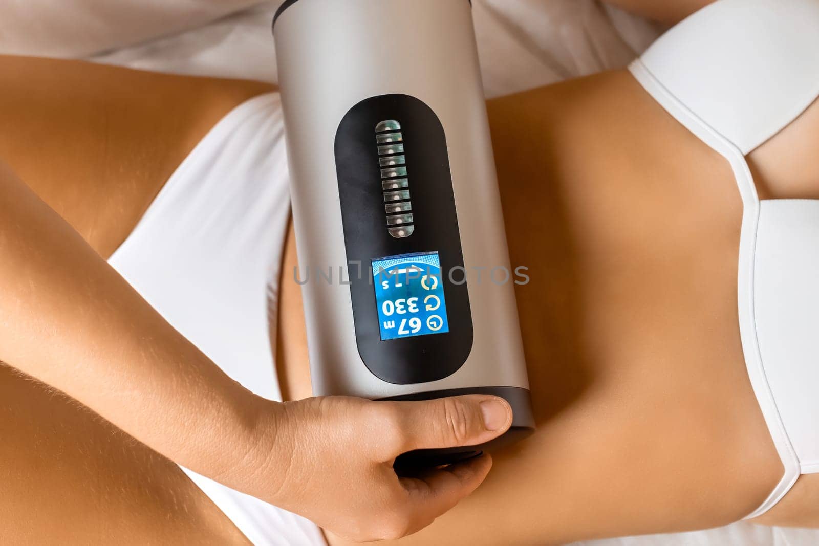 Female expert massages abdominal with fat burning device by vladimka