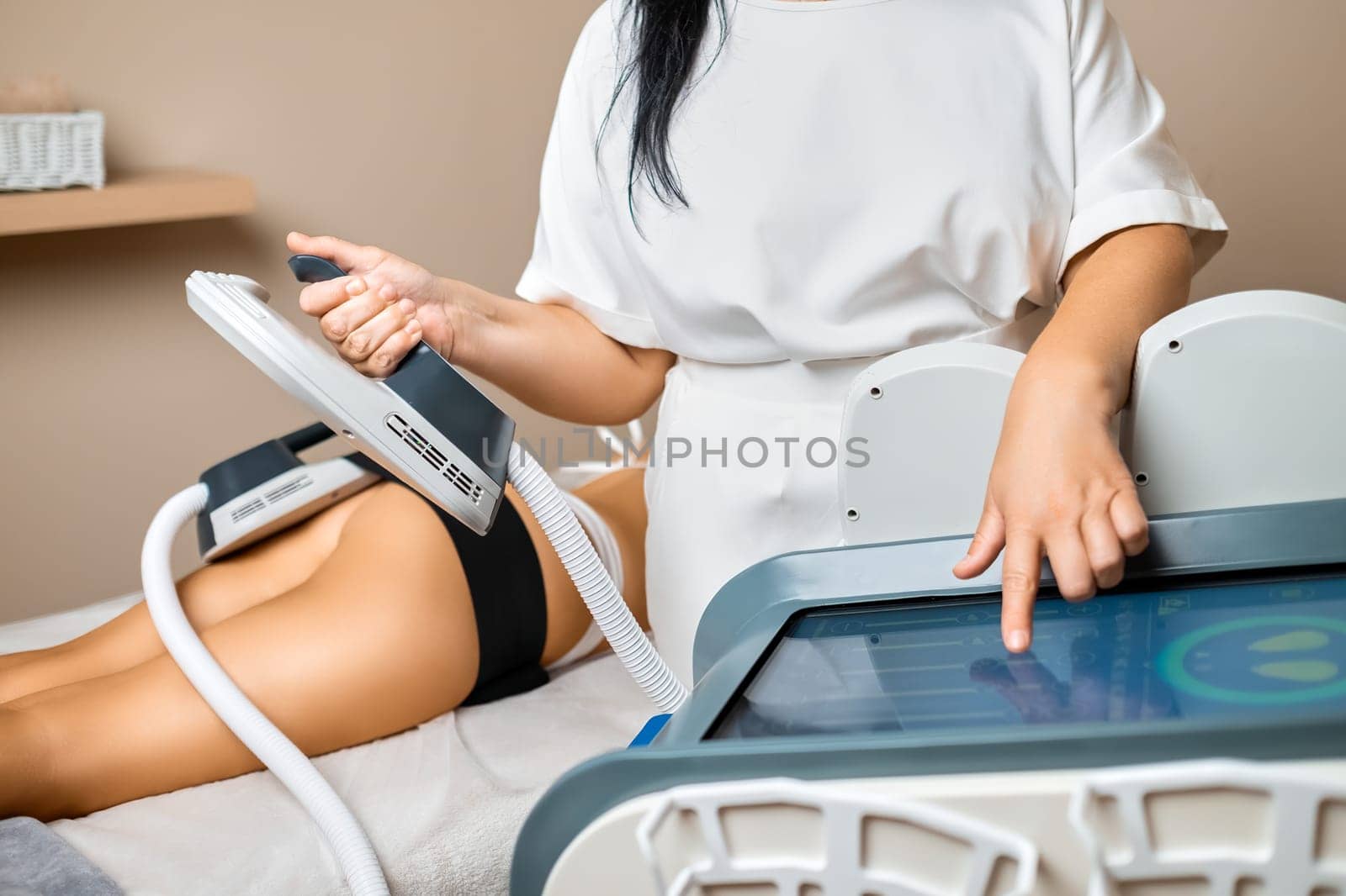 A woman worker in a beauty salon readies the equipment for a body sculpting procedure.