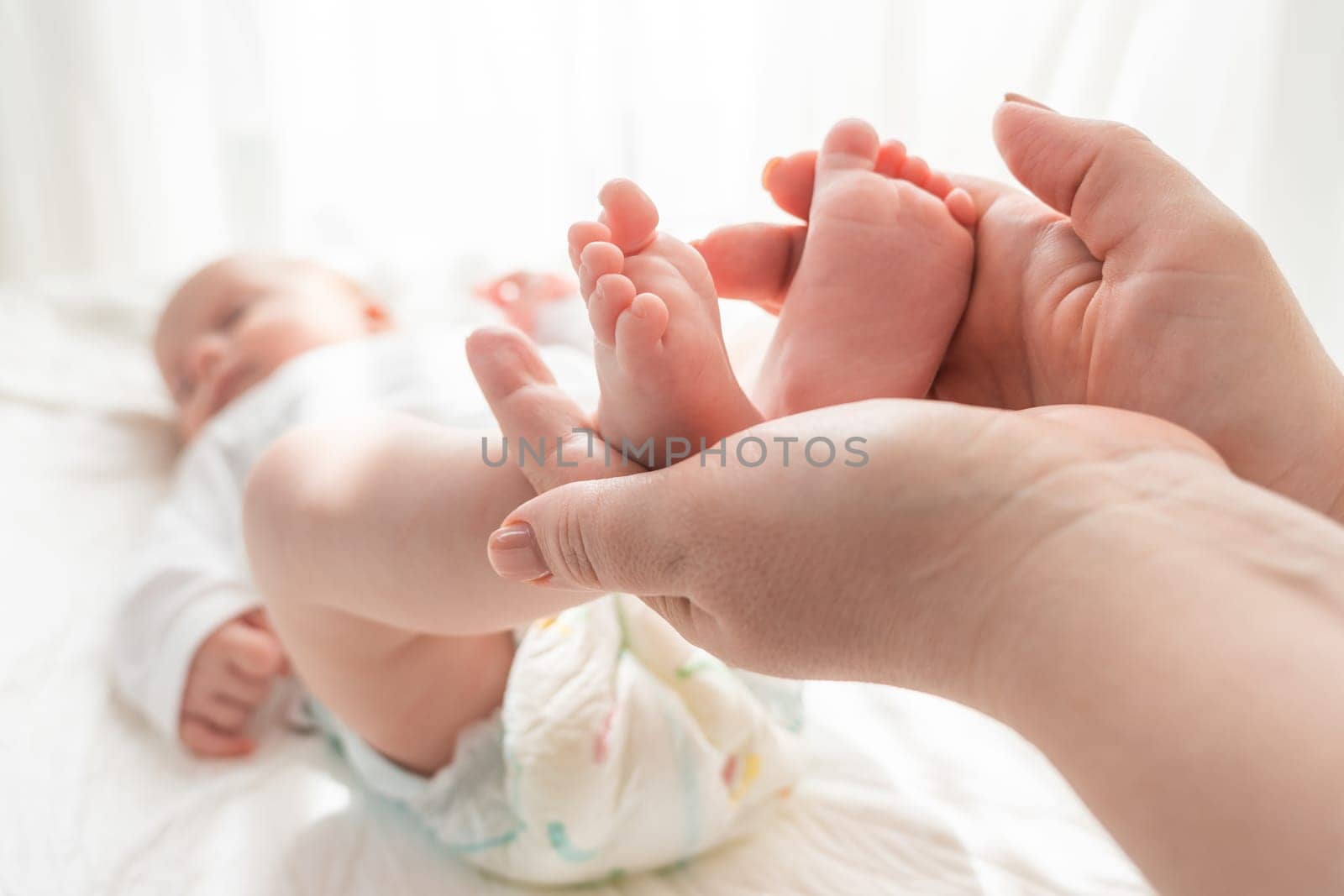 Mother's hands gently cradle the tiny feet of her newborn, showcasing pure love and bonding