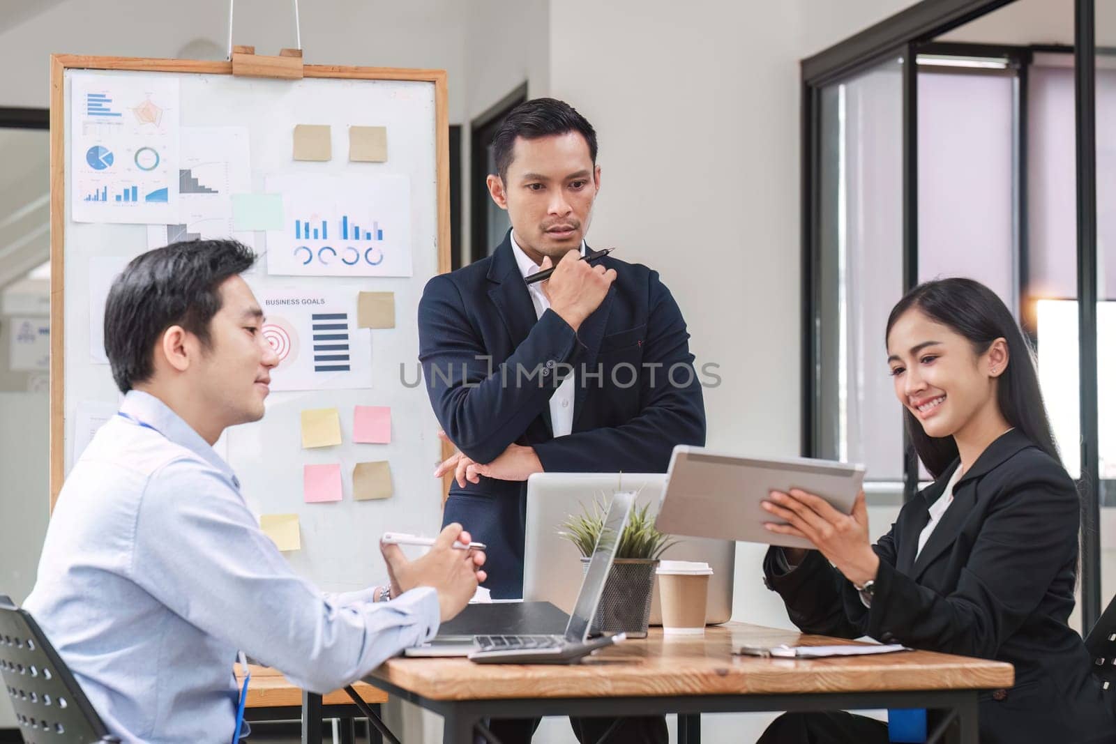 Professional businessman presenting to colleagues in conference room explaining growth chart by wichayada